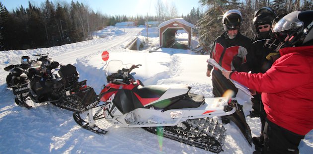 Snowmobilers and a covered bridge in Kamouraska